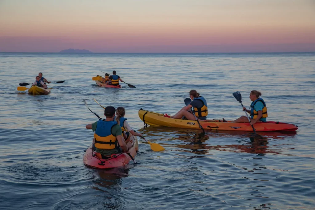 Kayak au coucher de soleil en Corse Groupe de kayakistes pagayant en mer au coucher du soleil en Corse.