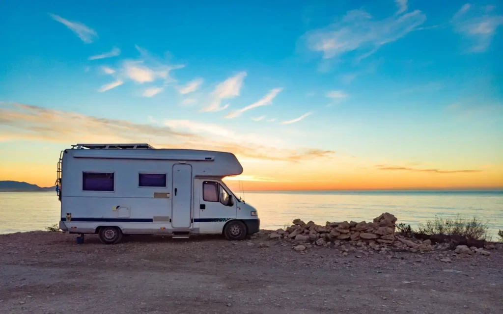 camping-car-mer-coucher-soleil Camping-car à capucine stationné sur une falaise en bord de mer face au coucher de soleil.