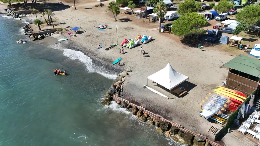 Base nautique sur la plage du camping Merendella avec kayaks, paddles et pédalos.