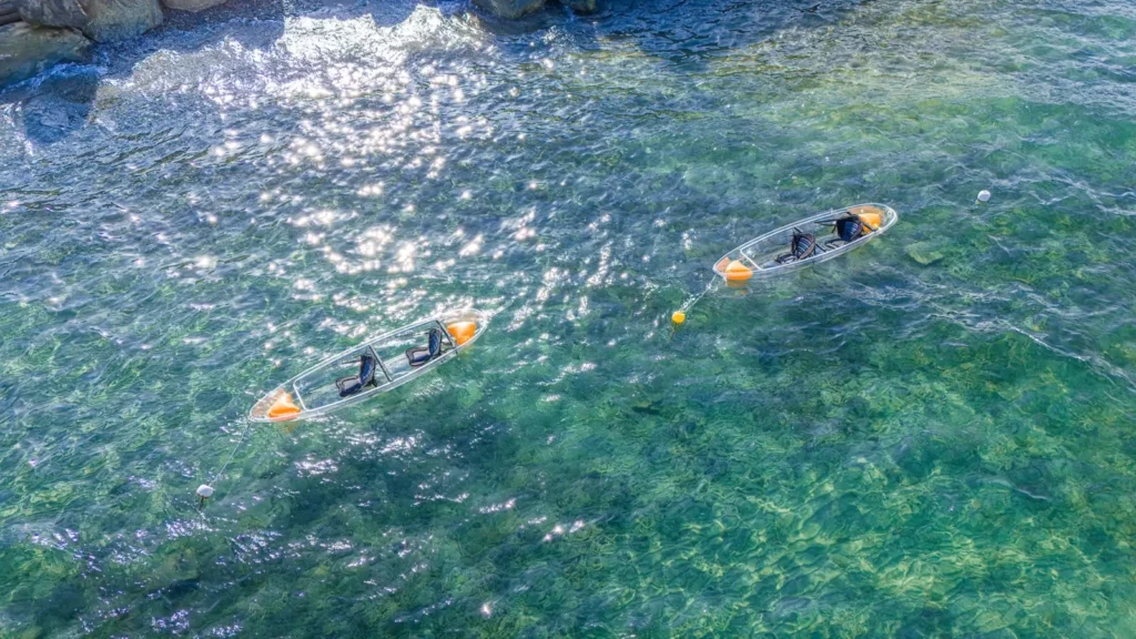 Zwei durchsichtige Kajaks schwimmen auf dem türkisfarbenen Wasser von Moriani-Plage auf Korsika.